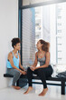 © SunriseDon/peopleimages.com - Laughing, phone and women on yoga class break for support, wellness or share health advice. Relax, mobile app or friends on floor talking in discussion or gossip together for news, resting or pilates