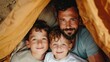 © Intelligent Horizons - A father and his two young sons are building a cozy blanket fort together in the living room creating a safe imaginative hideaway for playful adventure and family bonding time