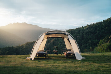 a tent in the woods with trees and green grass. taken during an afternoon with warmth from sunlight.