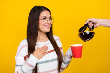 Sticker - Portrait of middle age working in office lady thankful teapot and pouring some hot black tea inside cup isolated on yellow color background