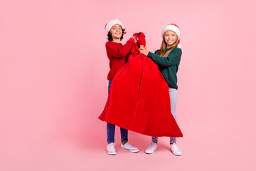 Poster - Photo of two people kids hold big red santa claus sack isolated pastel color background