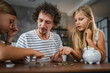 © Miljan Živković - Father with daughters save coins, money in the piggy bank at home