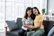 © Wasana - Two women sitting on a couch, one wearing a yellow shirt