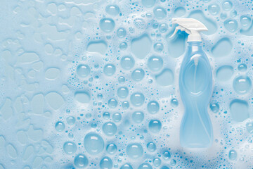 Cleaning spray bottle in soapy lather background with copy space