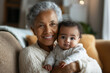 © Carmen - African-American grandmother holding her infant granddaughter, cozy living room setting, copy space