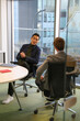 © Caia Image - Businessmen talking in office; Two businessmen talking at table in modern office