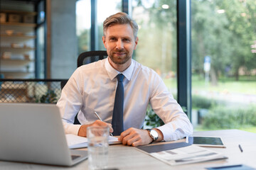 Portrait of young man sitting at his desk in the office.