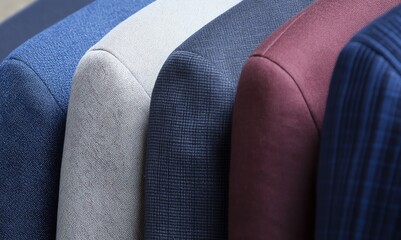 Various suit jackets, showing the shoulders as if hung on a rack; various fabrics, textures and colors