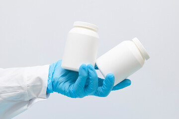 the pill bottle, medicine container for vitamins in female hand in blue gloves on grey background.