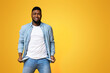 © Prostock-studio - I'm broke. Desperate black man showing empty turned out pockets over yellow studio background