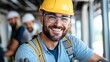 © LifeMedia - A construction worker smiles warmly at the camera, dressed in a yellow helmet and safety goggles, while working indoors on a construction site, with colleagues in the background.