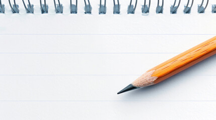 A close-up view of a blank notebook page with a sharpened pencil resting beside it, ideal for notes or creative ideas.