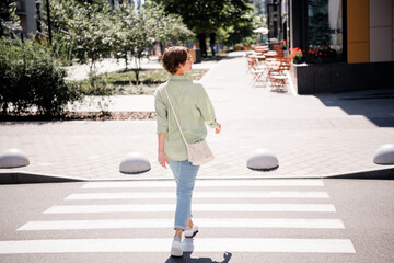 Wall Mural - Full length photo of cheerful adorable girl pedestrian wearing stylish clothes passing crossroad cityscape