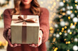 © Medical Works - Hand of woman offer gift box to lovers on christmas tree light background. have a copy space for text. Close up on woman hands giving Christmas present. Christmas gift.