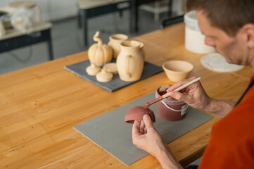 Potter paints ceramic dishes with a brush.