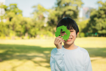 Wall Mural - Cheerful young asian boy holding recycle symbol on daylight natural green park promoting waste recycle, reduce, and reuse encouragement for eco sustainable awareness for future generation. Gyre