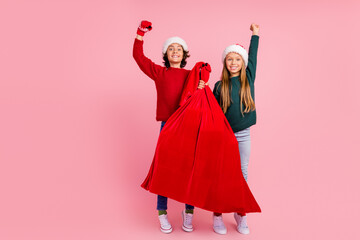 Poster - Photo of two people kids hold red santa claus sack raise fists up isolated pastel color background