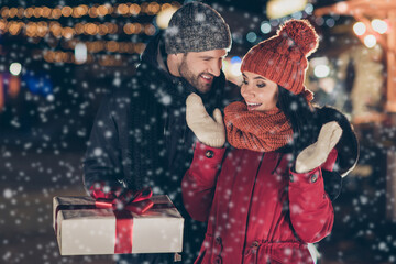 Wall Mural - Photo of guy delivering pretty lady x-mas giftbox with red bow newyear tradition wearing warm coats knitted caps and scarfs outdoors