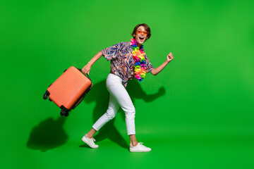 Poster - Full size photo of ecstatic girl wear print shirt necklace hurry go on plane in ariport with suitcase isolated on green color background