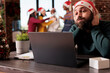 © DC Studio - Stressed tired company worker having burnout while managing workload on laptop in xmas decorated office. Exhausted caucasian man in santa hat sitting at workplace during new year holiday