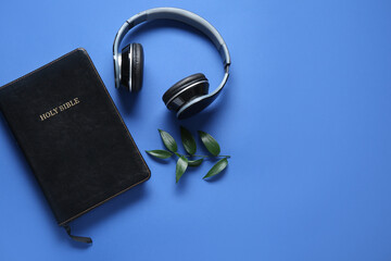 Wall Mural - Holy Bible with branch of eucalyptus and earphones on blue background