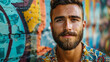 © SashaMagic - Young bearded man standing in front of a colorful graffiti wall.