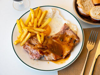 Sticker - Portion of hearty food o plate - two fried pork chops with bone, slices of crispy potatoes and fried egg fried