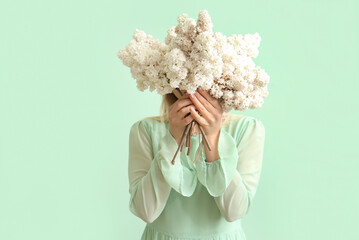 Wall Mural - Young woman with lilac flowers on green background