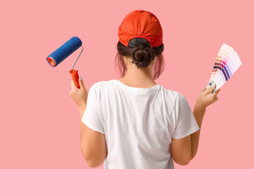 Wall Mural - young woman with paint roller and palette samples on pink background