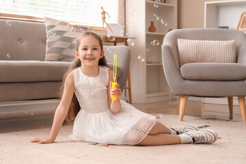 Sticker - Cute little girl blowing soap bubbles on floor at home