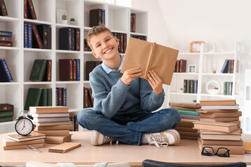 Poster - Teenage boy with books sitting on table in library