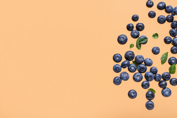 Wall Mural - Flying sweet fresh blueberries and leaves on orange background