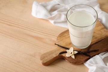 Sticker - Glass of fresh vanilla milk with sticks and flower on wooden background