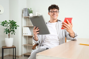 Sticker - Male accountant in eyeglasses with clipboard and calculator at workplace in office