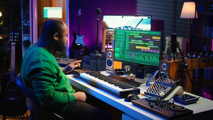 Poster - Sound engineer recording piano notes with DAW software in his home studio, working at night on producing new music with electronic tools. Musician composing tunes on midi controller. Camera B.