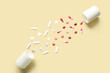 © Pixel-Shot - Bottle with flying pills on yellow background. Top view