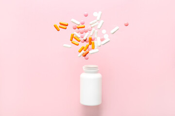 Wall Mural - Bottle with flying pills on pink background. Top view