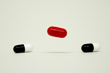 Sticker - Minimalistic display of a single red and black capsule on a white background emphasizing simplicity in medicine