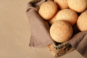 Poster - Wicker basket of fresh buns with sesame seeds on brown background