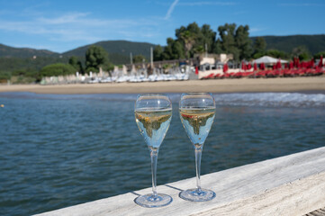 Summer time in Provence, two glasses of cold champagne cremant sparkling wine on famous Pampelonne sandy beach near Saint-Tropez in sunny day, Var department, France, beach club party