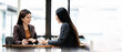 © NAMPIX - Two young Asian business woman talking, consulting and discussing working with new startup project idea presentation in the office.