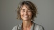 © Рудой Максим - Smiling woman with short wavy hair in gray shirt against a neutral background during a relaxed indoor setting