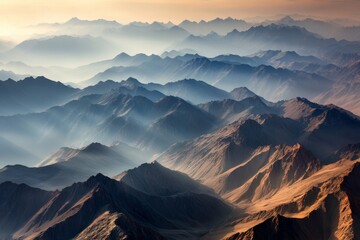 Wall Mural - Dawn breaks over the mountain range, casting golden light across the peaks and valleys, highlighting the rugged terrain and creating a serene atmosphere