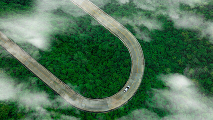 Poster - Aerial view of dark green forest road and white electric car Natural landscape and elevated roads Adventure travel and transportation and environmental protection concept