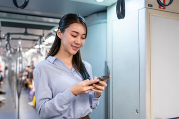 Wall Mural - Asian woman traveler using mobile phone device while riding on the train. 