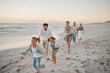 © Lumeez23/peopleimages.com - Parents, children and playful with running, beach and excited with grandparents on vacation in summer. Big family, kids and generations at sunset, care and bonding with games by ocean in Spain