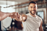 Happy man, fitness and fist bump with partner in success, workout or teamwork together at gym. Young male person, friend or men touching hands with smile for training, goal or exercise at health club