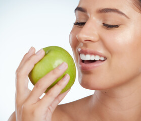 Poster - Model, smile or woman with apple for healthy nutrition, skincare or snack on white background in studio. Food diet, fiber and face of girl eating fruit for detox and vitamin c for organic benefits