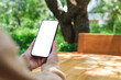 © Farknot Architect - Mockup image of a woman holding mobile phone with blank white desktop screen in the outdoors