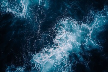 White ocean foam on a deep blue water surface, top view.